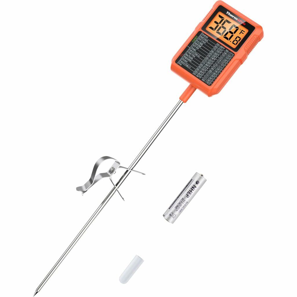 The ThermoPro TP510 Candy Thermometer with the pot clip beside it and a AAA battery beside it.